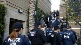 Federal agents enter an apartment complex March 3, 2015, in Irvine, Calif. to investigate a birth tourism business.