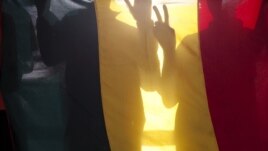 Malians gesture behind the national flag at a rally against the seizure of northern Mali by Tuareg and Islamist rebels, in Bamako (file photo).