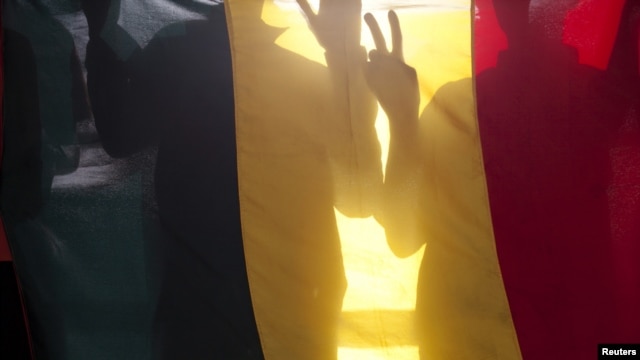 Malians gesture behind the national flag at a rally against the seizure of northern Mali by Tuareg and Islamist rebels, in Bamako (file photo).