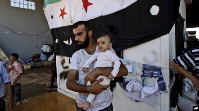 A Syrian man, who fled his home due to government shelling, holds his son as they take refuge at Bab Al-Salameh crossing border, hoping to cross to one of the refugee camps in Turkey, near the Syrian town of Azaz, Sept. 12, 2012.  