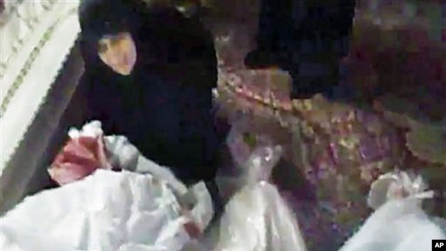 Image made from amateur video released December 27, 2011, purports to show a woman mourning over a relative who has been killed in Homs, Syria, December 26, 2011.