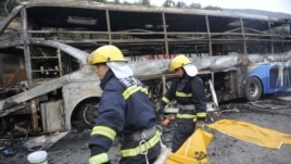 Firefighters carry a victim in a body bag as they work at the accident site after a collision between a bus and a methanol-loaded tanker occurred in Yan'an, Shaanxi province, August 26, 2012. 