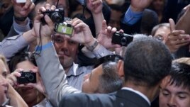 Members of the audience take photographs as President Barack Obama shakes hands at The National Association of Latino Elected and Appointed Officials’ Annual Conference at the Walt Disney World Resort in Florida, June 22, 2012.