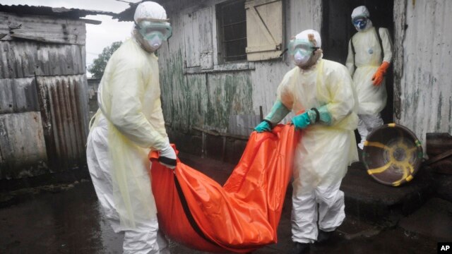 Health workers in protective gear carry the body of a woman suspected to have died from Ebola virus, from a house in New Kru Town at the outskirt of  Monrovia, Liberia, Oct. 8, 2014. 