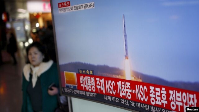 A passenger walks past a TV screen broadcasting a news report on North Korea's long range rocket launch at a railway station in Seoul, South Korea, Feb. 7, 2016.