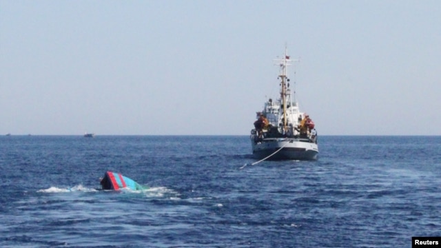 A Vietnamese sinking boat (L), which was rammed and then sunk by Chinese vessels near disputed Paracels Islands, is seen near a Marine Guard ship (R) at Ly Son island of Vietnam's central Quang Ngai province, May 29, 2014.