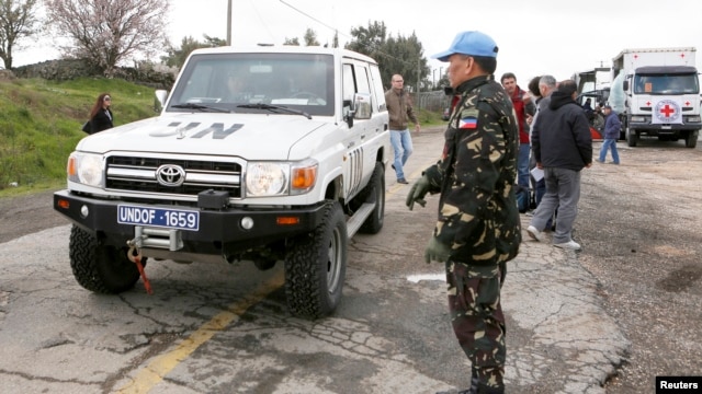 A Filipino United Nations peacekeeper stands next to a U.N. vehicle before it crosses from Israel into Syria at the Kuneitra border crossing on the Golan Heights, March 5, 2013. 