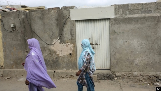 Local women walk past the locked house 