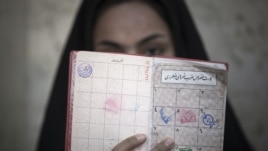 A woman holds her identification in front of her face after voting at a polling station during Iran's parliamentary election in southern Tehran, March 2, 2012.