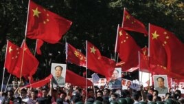 Demonstrators holding posters of China's late Chairman Mao Zedong, Chinese national flags and banners march past riot policemen during a protest on the 81st anniversary of Japan's invasion of China, outside the Japanese embassy in Beijing, September 18, 2