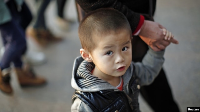 A boy walks with his grandmother at a commercial area of downtown Shanghai, November 28, 2012. 