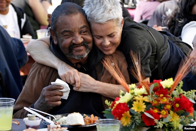 Richard Brown (L) is hugged by volunteer Jane Johnson during Thanksgiving meal served to the homeless in 2013