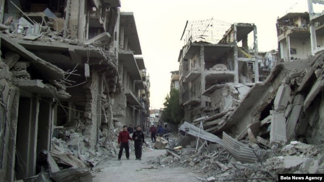 Syrian citizens walk in a destroyed street that was attacked on Wednesday by Syrian forces warplanes, at Abu al-Hol street in Homs province, Syria, Nov. 29, 2012.