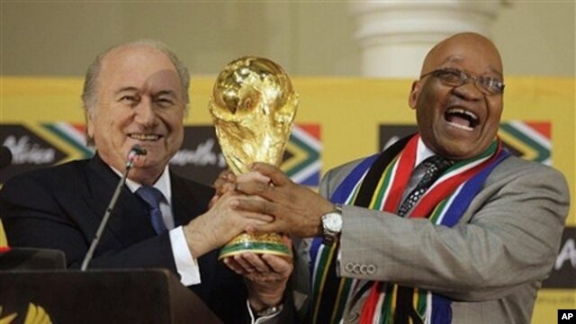 South African President Jacob Zuma, right, laughs as he hands over the trophy to FIFA President Joseph Blatter, left, during the briefing to local and international media on the 2010 Soccer World Cup at the Presidential Guest House in Pretoria, South Afri