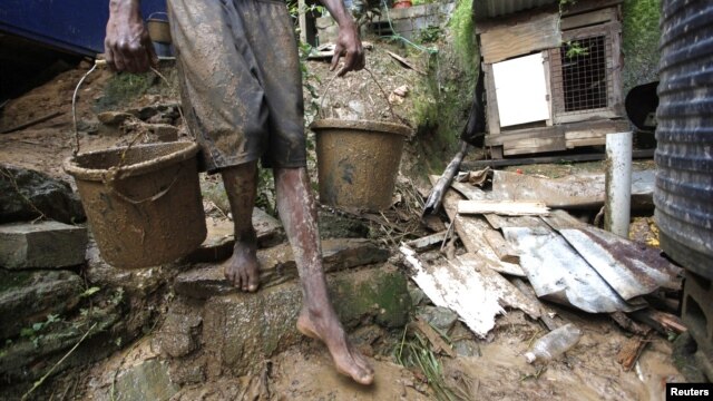 Un hombre saca lodo de una casa en una ladera en Scorpion Alley, Carenage, a unos 10 kilómetros de Puerto Príncipe, Haití, donde las lluvias torrenciales de Isaac han causado algunos daños materiales.
