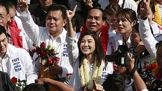 Opposition leader of Phue Thai party, Yingluck Shinawatra, center, flashes a number one sign as she arrives for the registration of constituency candidates competing in upcoming general election in Bangkok, May 24, 2011.