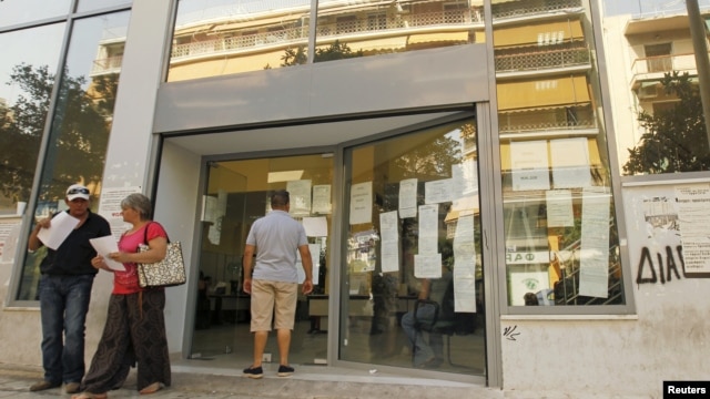 A man checks announcements outside an unemployment bureau in Athens, Greece, August 9, 2012.