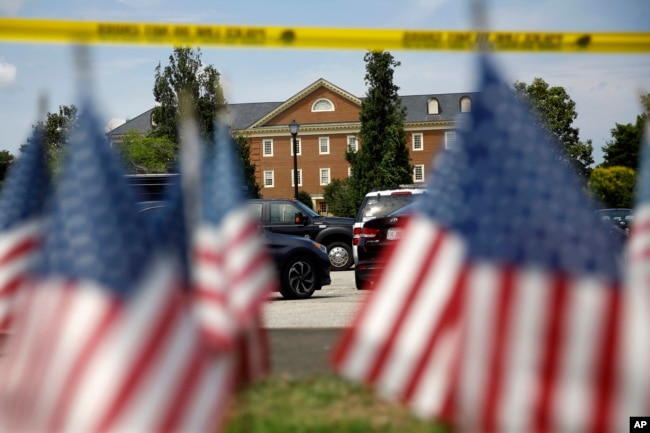 Banderas estadounidenses forman parte de un altar improvisado al borde de un cordón policial frente a un edificio municipal que fue el escenario de un tiroteo, el sábado 1 de junio de 2019, en Virginia Beach, Virginia.
