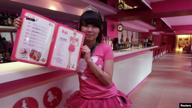 Seorang pelayan di kafe bertema Barbie berpose dengan buku menu. (Reuters/Pichi Chuang)