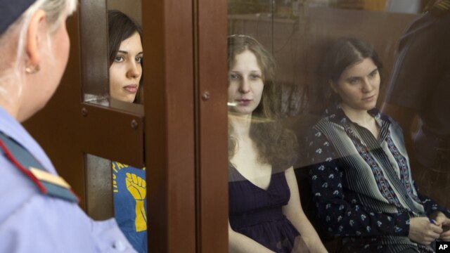 Feminist punk group Pussy Riot members, from left, Nadezhda Tolokonnikova, Maria Alekhina and Yekaterina Samutsevich sit in a glass cage at a court room  in Moscow, Russia, August 8, 2012. 
