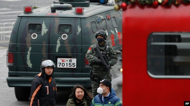 中国武警2015年12月27日在北京三里屯巡逻，可见行人经过警车。