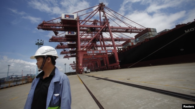 An employee stands next to a container ship at Ningbo port in Ningbo, Zhejiang province, June 21, 2012. 