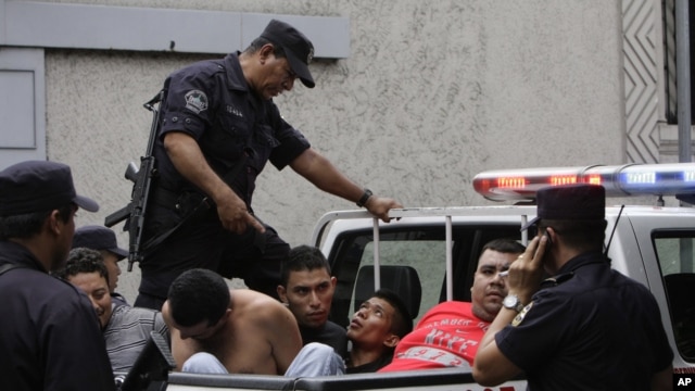 In this Aug. 31, 2012 photo, alleged members of the MS-13 or Mara Salvatrucha gang arrested on murder and gun possession charges are loaded into a police pick-up truck after being presented to the press in San Salvador, El Salvador. 