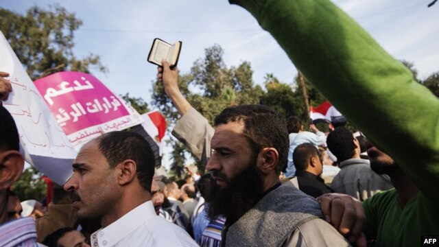 A man holds a copy of the Quran during pro-Morsi rally outside Cairo University, Dec. 1, 2012.