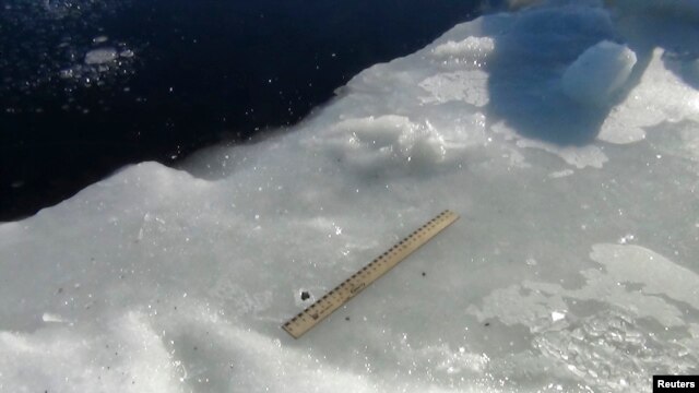 Científicos utilizan una regla para medir los fragmentos del meteorito encontrados alrededor del lago.
