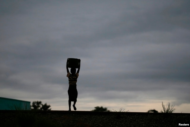 Storm clouds loom as a child carries water from a communal borehole near the capital Lilongwe, Malawi, Feb. 2, 2016. Floods and an El Nino-triggered drought have hit the staple maize crop in the country, a former food exporter.