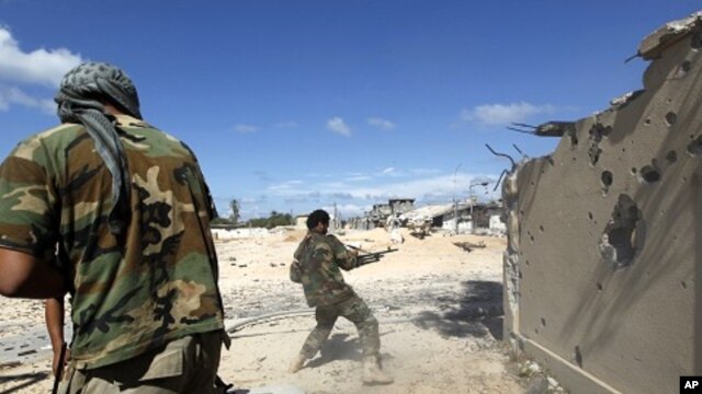 Anti-Gadhafi fighters return fire during clashes with pro-Gadhafi forces in the center of Sirte October 17, 2011.