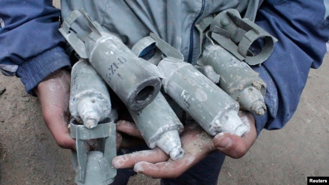 A boy holds unexploded cluster bombs after jet shelling by forces loyal to Syria's President Bashar al-Assad in the al-Meyasar district of Aleppo, Feb. 21, 2013.   