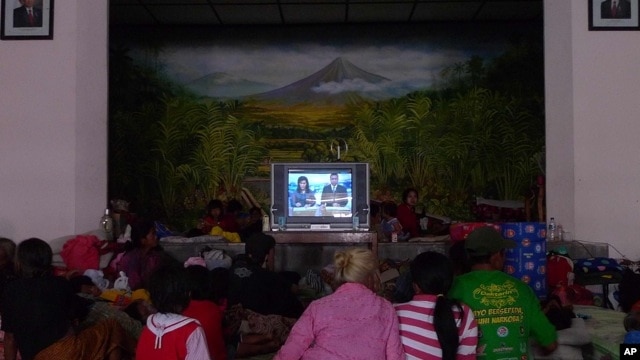 Evacuees gather to watch television to stave off boredom at the Wonokerto evacuation shelter