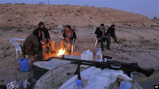 Libyan anti-government fighters sit by a fire to stay warm as they control a checkpoint on the outskirts of the southwestern town of Nalut, Libya, February 28, 2011