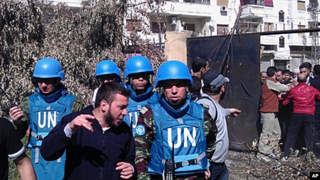 A handout picture released by the Syrian opposition's Shaam News Network shows Syrian residents talking to Moroccan UN observer, Colonel Ahmed Himmiche (R) during the monitors' visit to the Khalidiya district in the restive city of Homs, April 21, 2012.  