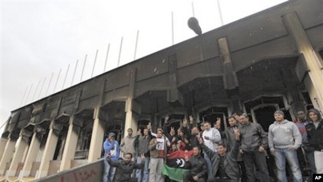 Libyan youth gather for a souvenir picture at the entrance to the burned house of Libyan Leader Moammar Ghadafi inside Al-Katiba military base, in Benghazi, Libya, February 27, 2011