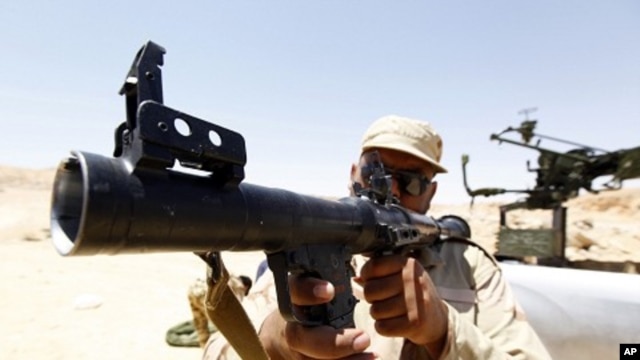 A rebel fighter inspects the condition of a rocket launcher captured from troops loyal to Muammar Gaddafi near the town of Bir al-Ghanam, about 100km (62 miles) south of Tripoli, June 30, 2011.