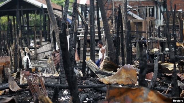 A man walks through a neighborhood that was burnt in recent violence in Sittwe, June 16, 2012.
