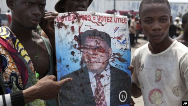 Opposition UDPS members hold up blood-splattered poster of leader Etienne Tshisekedi after presidential guard opened fire on crowd outside N'Djili airport in Kinshasa, November 26, 2011.