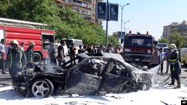 Ảnh do thông tấn xã chính thức của Syria phát hành cho thấy lính cứu hỏa dập tắt đám cháy xe sau vụ nổ bom tại khu vực phía tây thủ đô Damascus, ngày 29/4/2013.