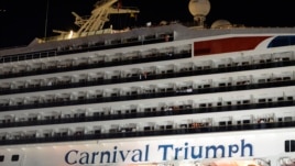 People watch from their balconies and hold up signs aboard the Carnival Triumph after it was towed to the cruise terminal in Mobile, Ala., February 14, 2013.