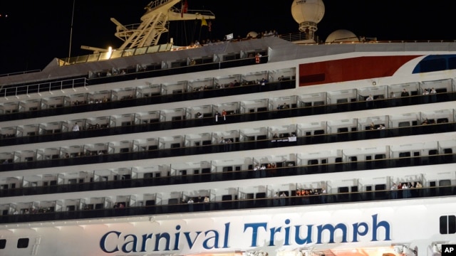 People watch from their balconies and hold up signs aboard the Carnival Triumph after it was towed to the cruise terminal in Mobile, Ala., February 14, 2013.