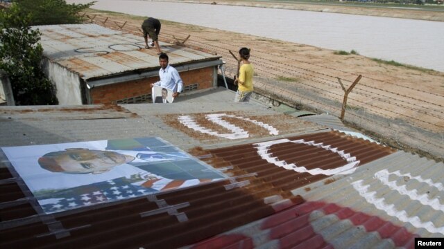 People display portraits of U.S. President Barack Obama on the roof of their houses near Phnom Penh Airport November 14, 2012. Around 182 families living around the airport have been served with eviction notices ahead of Obama's historic visit to the country.