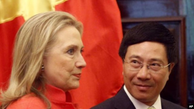 Vietnam's Foreign Minister Pham Binh Minh (R) looks at U.S. Secretary of State Hillary Clinton as they walk to the meeting room at the Government Guest House in Hanoi, July 10, 2012. 