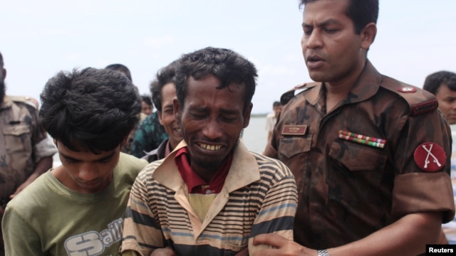 A member of Border Guards of Bangladesh comforts a Rohingya from Burma who was arrested while trying to get into Bangladesh, in Teknaf, June 18, 2012.