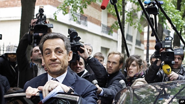 French President and UMP party candidate for the elections Nicolas Sarkozy, left, prepares to enter a car as he leaves his campaign headquarters the morning after the first round of voting in Paris, April 23, 2012. 