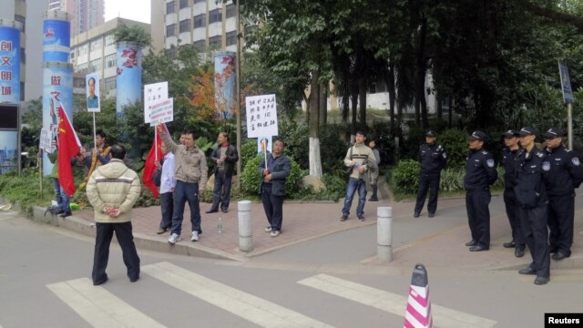 Para pengunjuk rasa memegang spanduk, potret almarhum pemimpin Tiongkok Mao Zedong, dan bendera Tiongkok di dekat barisan polisi yang berjaga di luar kantor pusat surat kabar Southern Weekly di Guangzhou, propinsi Guangdong. (8/1)