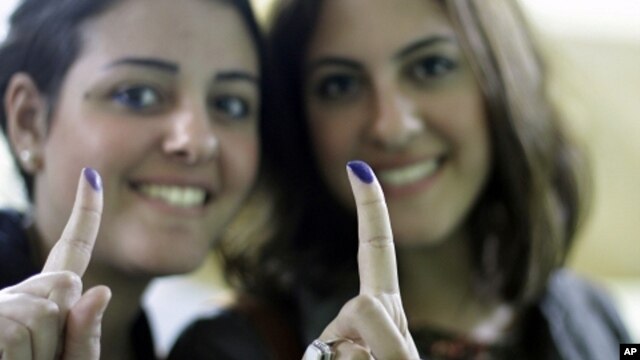Egyptian women show their inked fingers after voting in Cairo, Egypt, Monday, Nov. 28, 2011