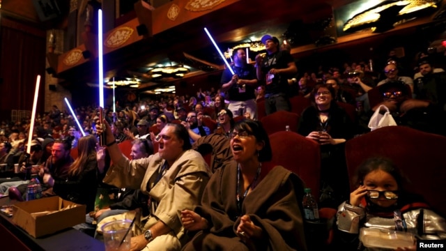 FILE - Moviegoers cheer and wave lightsabers at "Star Wars: The Force Awakens" at the TCL Chinese Theatre in Hollywood, California, Dec. 17, 2015.