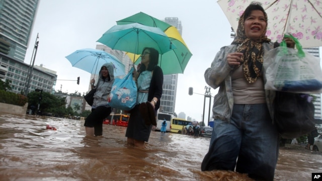 Women wade through a flooded street in Jakarta, Indonesia, January 17, 2013.